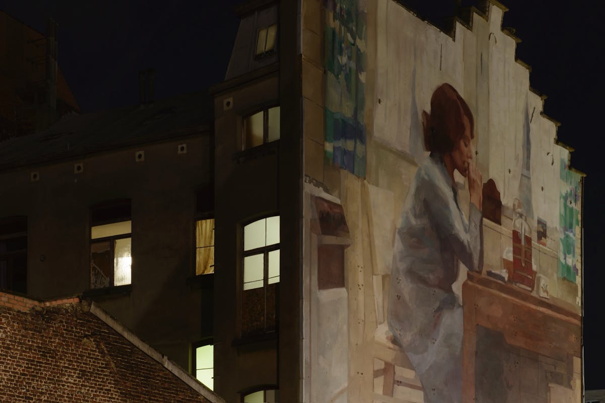 Muurschildering van een scène uit Jeanne Dielman, 23, quai du Commerce, 1080 Bruxelles van Chantal Akerman, op de hoek van de Schuitenkaai en de Sint-Andriesstraat in Brussel, foto Chantal van Rijt